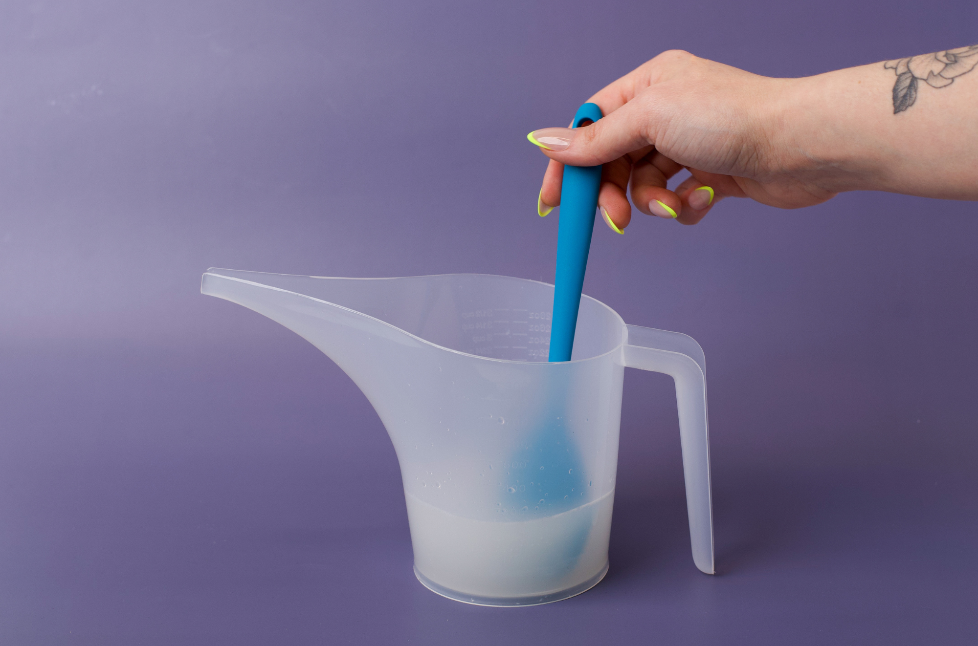 Mixing all ingredients together with a spatula in a pouring pitcher.